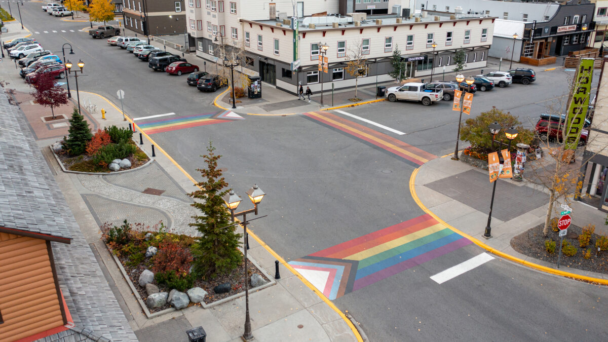 A drone photo of the crosswalks at Front Street and Main Street. The crosswalks have been painted with the colours of the Progress Pride flag and BIPOC flag.