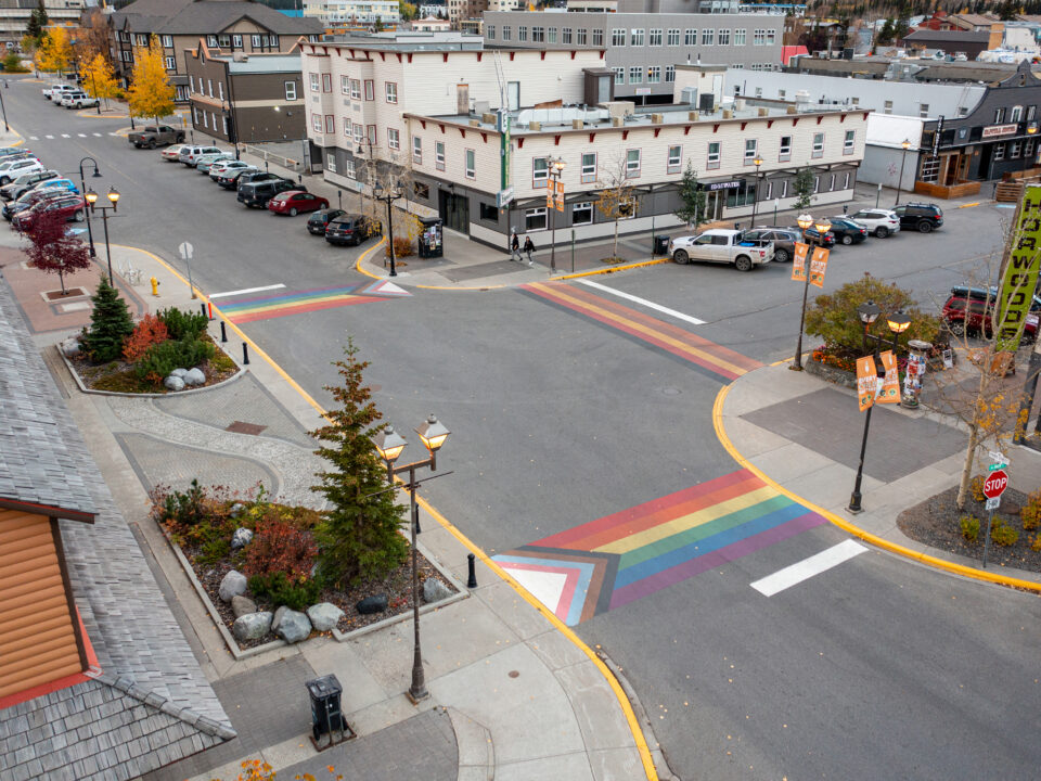 A drone photo of the crosswalks at Front Street and Main Street. The crosswalks have been painted with the colours of the Progress Pride flag and BIPOC flag.